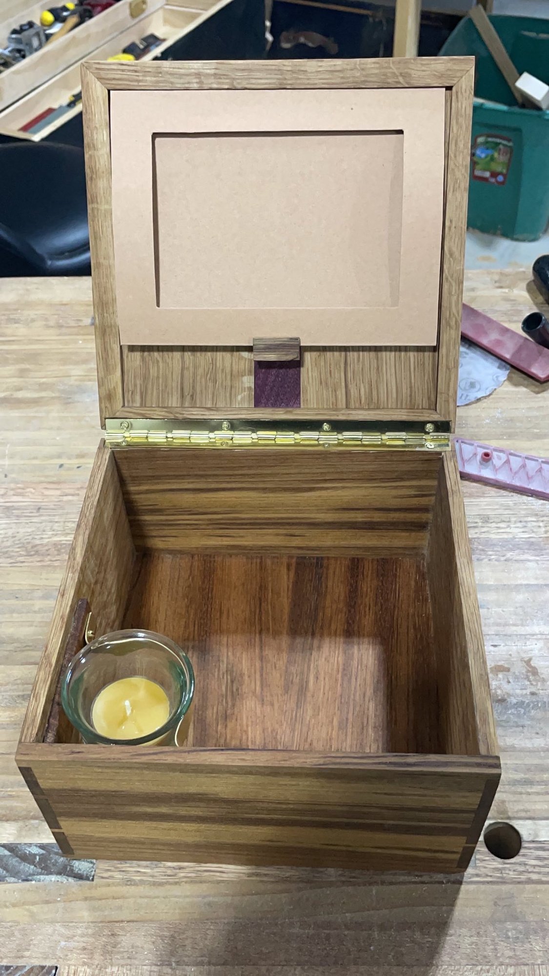 Box open: photo ledge inside the lid, lignum vitae floor, beeswax votive in a small glass at the front corner.