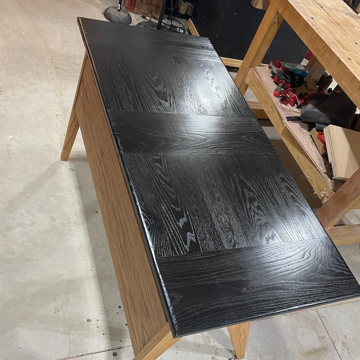 Angled view of the ebonized top, oak grain still visible through the black, natural base underneath.