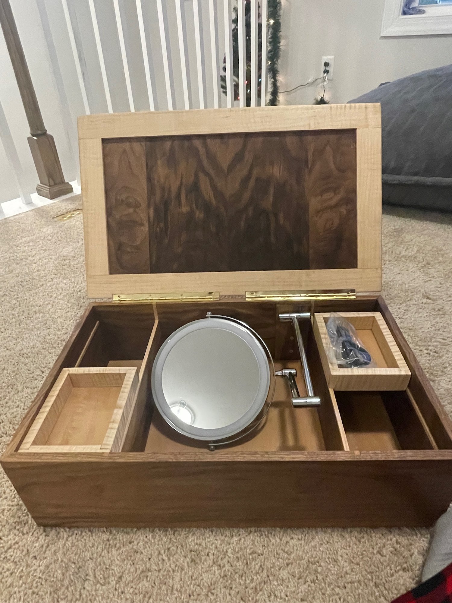 Box open: rechargeable lighted mirror in the center, tiger maple trays on either side, figured walnut inside the lid.