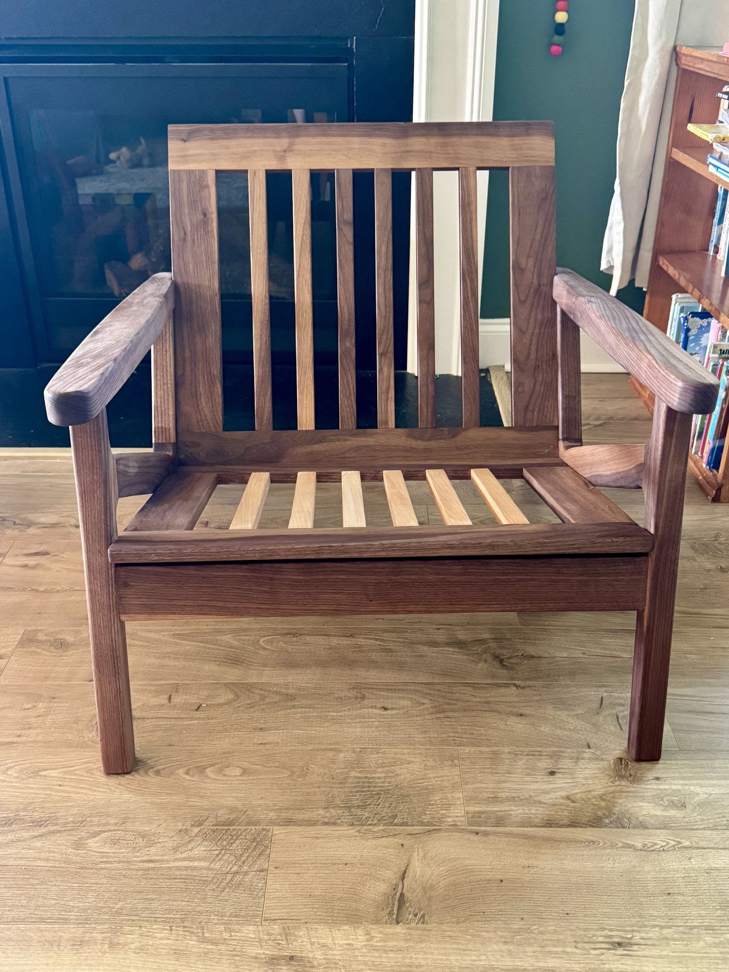 Front view of the walnut lounge-chair frame without cushions, showing slatted back, seat slats, and wide arms.