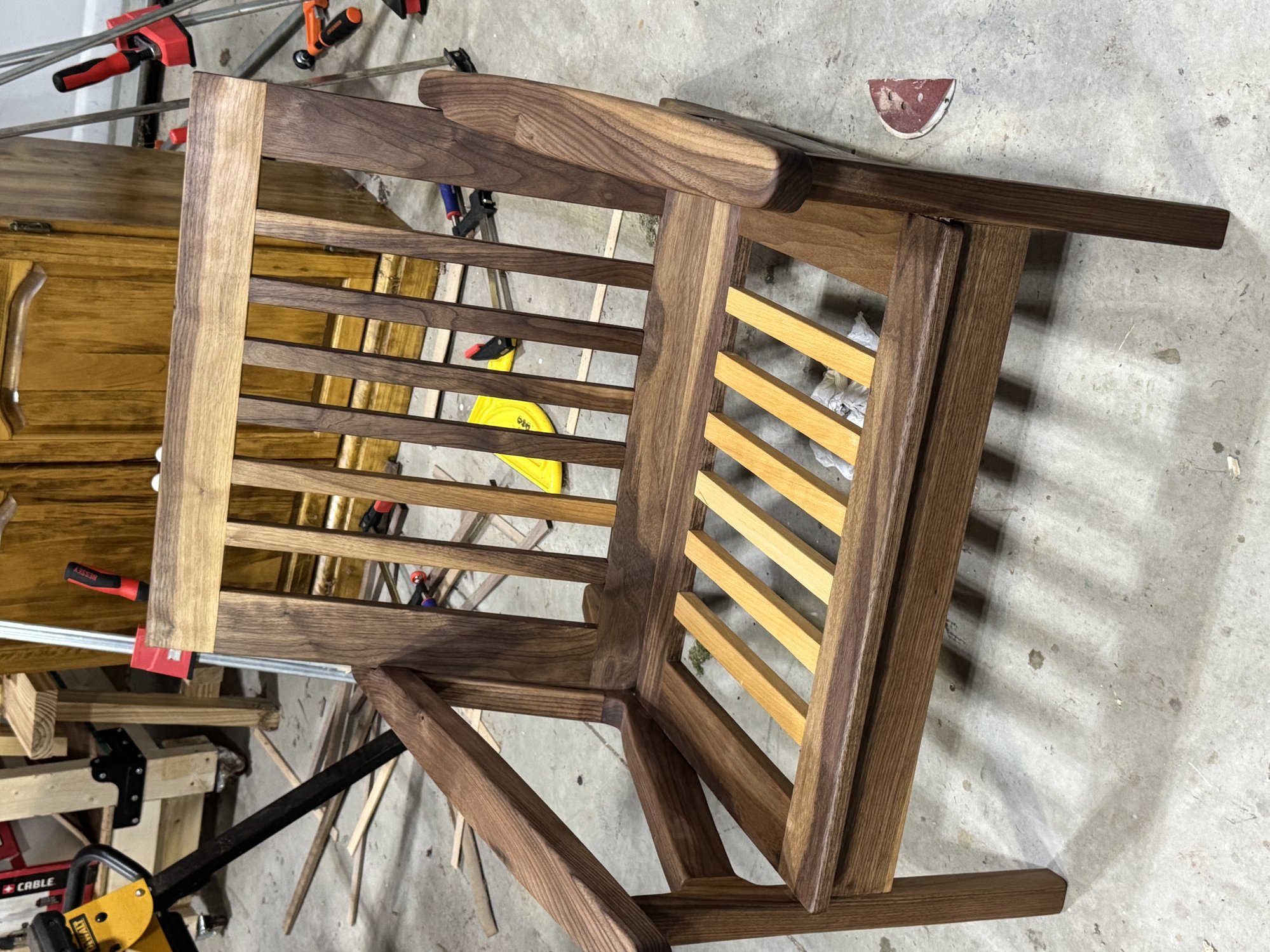 Workshop overhead-front view of the walnut chair frame, showing the slatted back, seat slats, and wide arms.