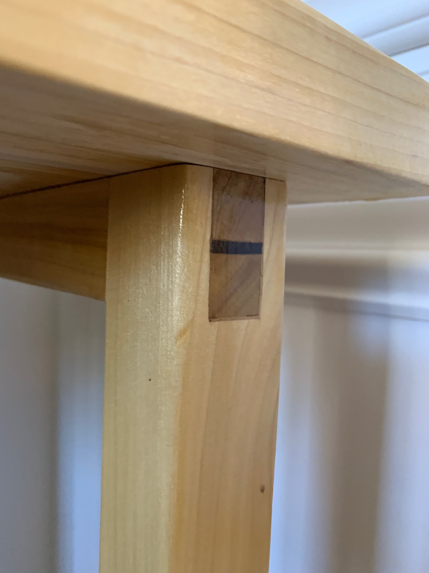 Close-up of a wedged tenon: walnut wedge driven through a poplar tenon in the leg.