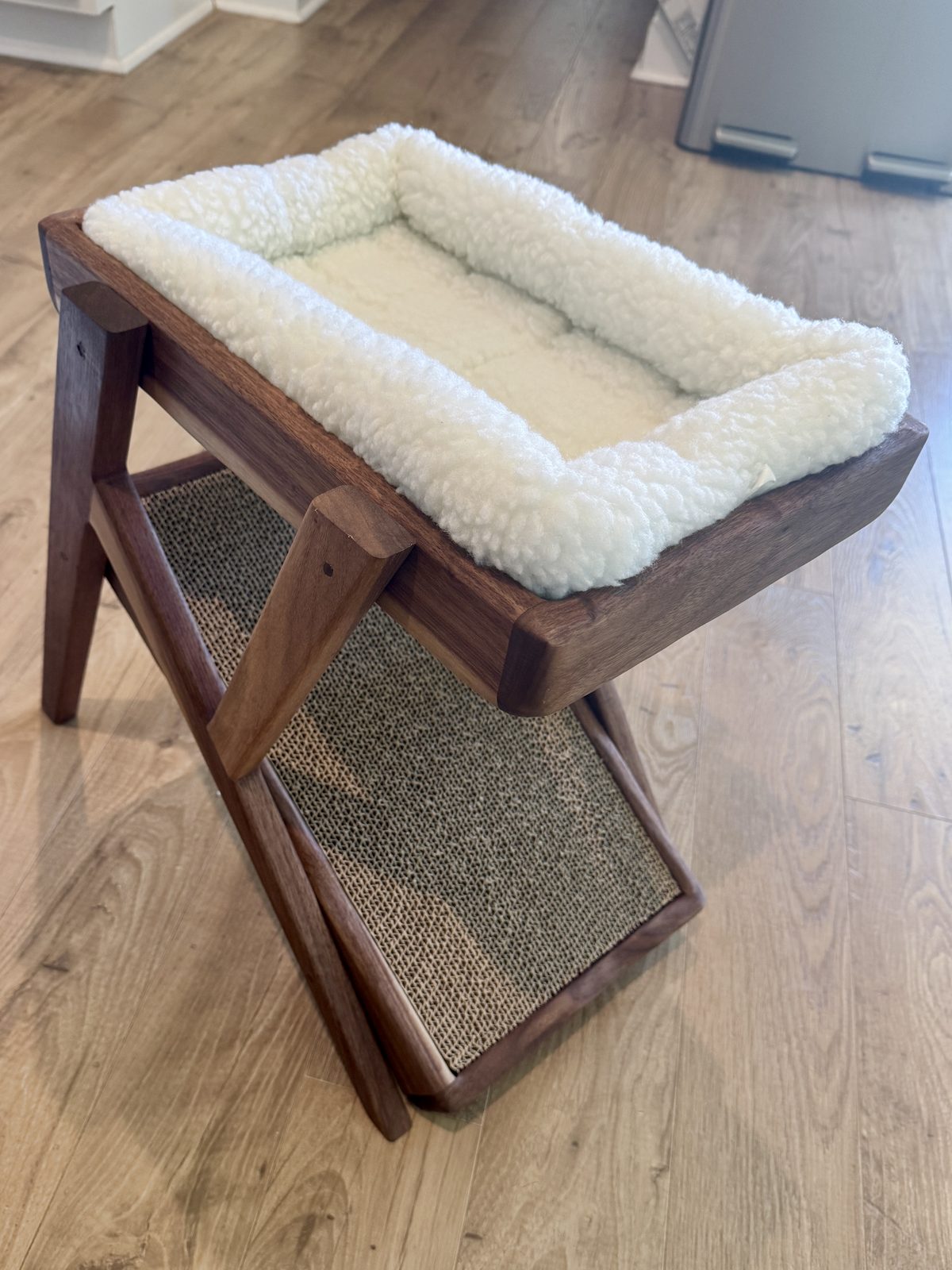 Side view of the walnut cat bed showing the sherpa nest and the inclined cardboard scratch ramp.